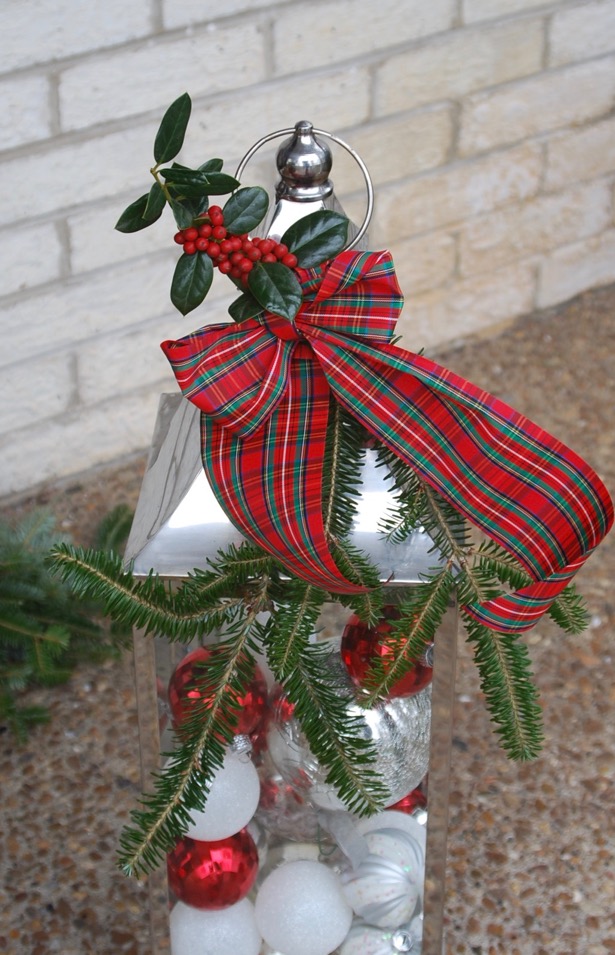 A traditional Christmas Front Door with plaid ribbon, garland, holly wreaths, and lanterns