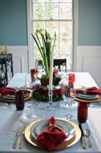 Set an elegant red and white Christmas table with paperwhite centerpiece, boxwood, and magnolia for Christmas dinner