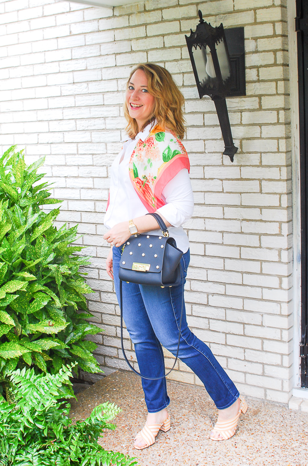 Blond woman in preppy wardrobe staples: white oxford, dark wash denims, heels, and scarf.