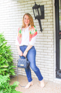 Young blond in preppy wardrobe staples: white oxford, dark wash denims, heels, and scarf.
