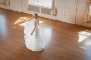 Bridal portrait of young woman in wedding dress dancing in ballroom.