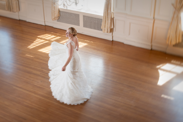Bridal portrait of young woman in wedding dress dancing in ballroom.
