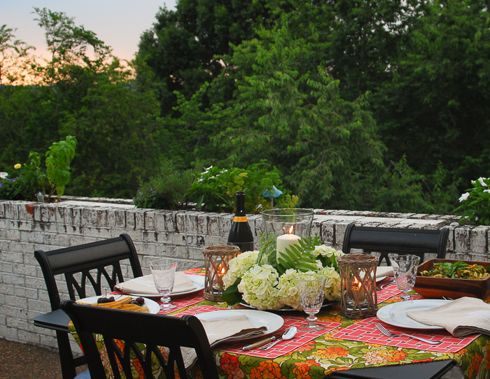 Table set for al fresco summer dining with hydrangea centerpiece and vibrant linens