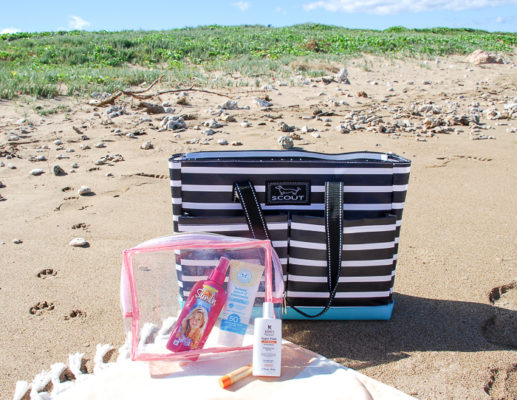 Striped beach bag in the sand with beach skin care products