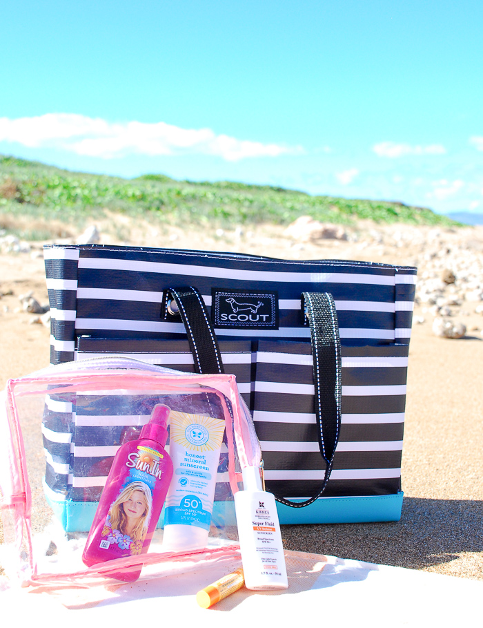 Striped beach bag in the sand with beach skin care products