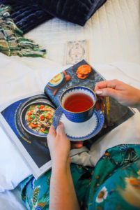 Warm cozy evening in comfy bed with cup of tea and magazine