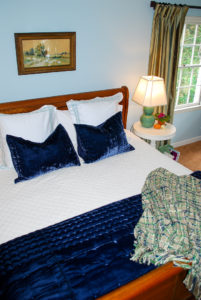 Overhead shot of the coziest comfy bed for autumn made up with 400 thread count sheets, velvet bedding, and a pillow pile