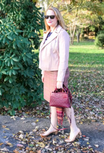 Blonde woman wearing pink moto jacket, plaid skirt, and tee for 5 winter plaid pieces you need in your wardrobe