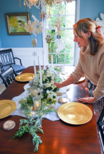 Winter tablescape tutorial - woman adjusts florals
