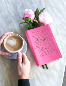 French cafe table with copy of Emma by Jane Austen, latte, and pink peonies