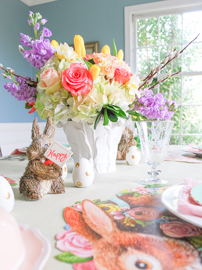 Vibrant floral centerpiece with pink roses, yellow tulips, hydrangea, pussy willow, and purple gillyflowers for a pastel Easter brunch table