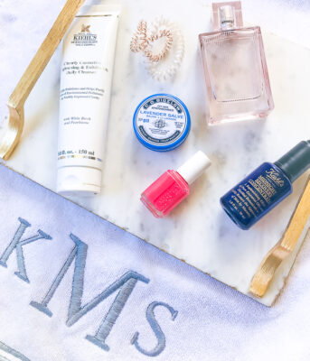 flatlay of 6 spring beauty must haves on marble tray with monogrammed towel