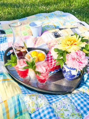 blueberry lemon mint fizz cocktails on a tray with peonies and patchwork quilt underneath