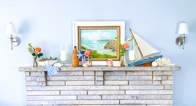 Get in a summer state of mind with this nautical summer mantel with vintage decor, featuring a sailboat, coral, seashells, and wicker.
