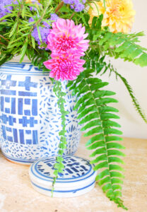 Detail view of pink dahlias and sweeping fern down side of ginger jar