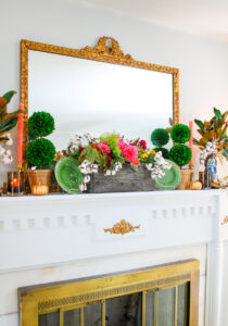 traditional fall mantel with fall dish garden, boxwood topiaries, majolica spaniels, magnolia, and gilt mirror.