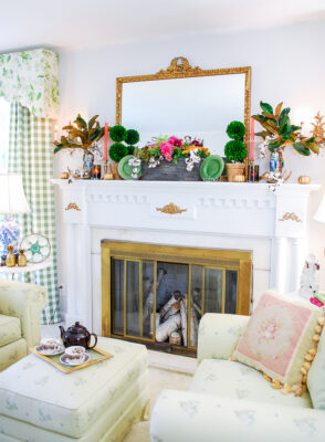 traditional fall mantel with fall dish garden, boxwood topiaries, majolica spaniels, magnolia, and gilt mirror.