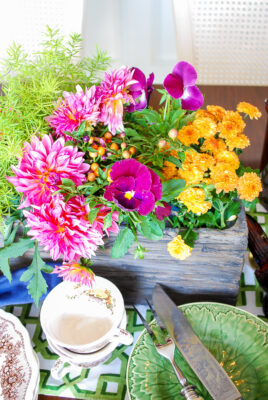 Purple pansies, pink dahlias, and yellow mums spill out of this fall centerpiece