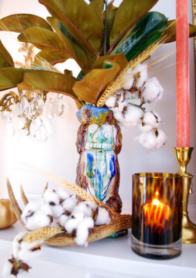 Majolica spaniel pitcher filled with magnolia, cotton, and wheat with tortoise shell candle holder