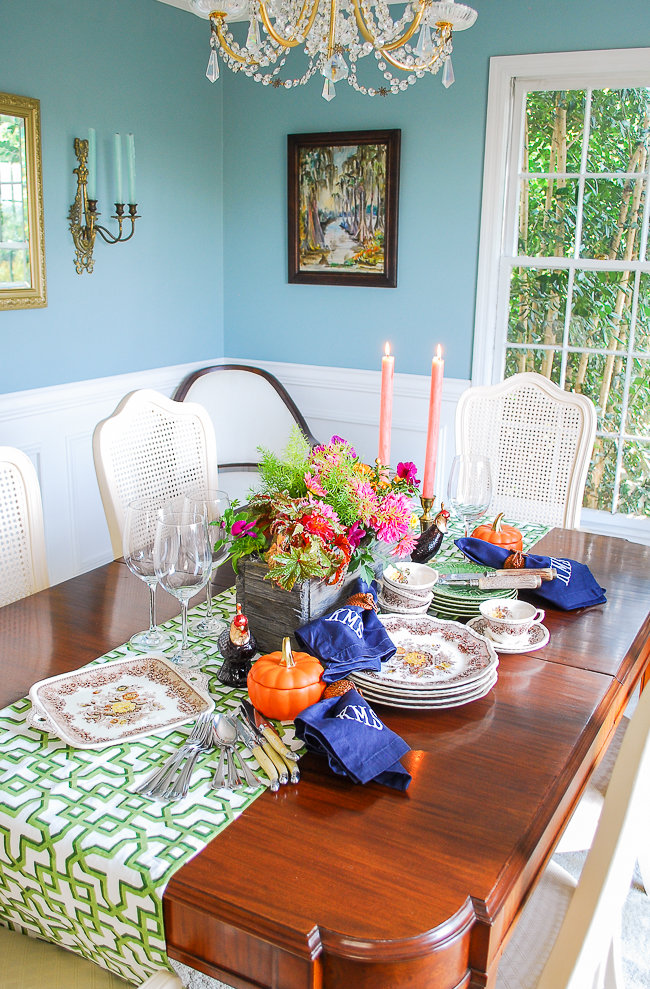 A traditional dining room set with a Southern autumn table featuring mini pumpkins, fall themed china, candle light, and monogrammed napkins