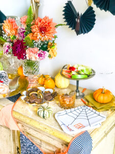 Eeeek plates, paper bats, and a flag garland decorate this Halloween treat bar filled with yummy desserts.