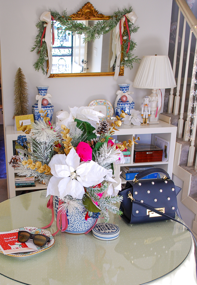 Front entry table with white poinsettia floral arrangement in blue and white ginger jar