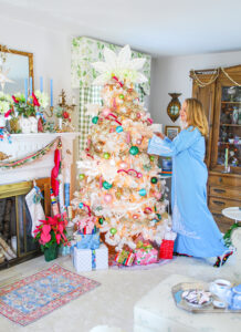 Katherine of Pender & Peony in blue vintage caftan decorates her white Christmas tree with colorful ornaments