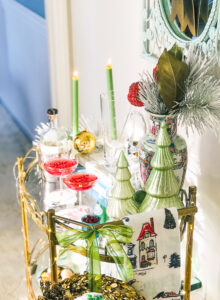 Gold bar cart styled for holidays with candles, glass Christmas trees, Rose Medallion, and wreath