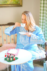 Katherine of Pender & Peony sitting on settee sipping tea in blue caftan