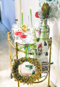 Gold bar cart styled for holidays with candles, glass Christmas trees, Rose Medallion, and wreath