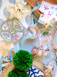 flatlay design board with grandmillennial decor, including boxwood, chinoiserie, magazine clippings, tassels, ribbon, chintz, and wicker