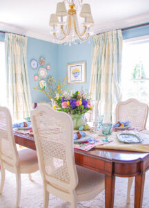 Dining table set with fresh traditional Easter tablescape in bright pastels, spring florals, and April Cornell placemats.
