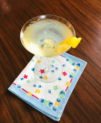 An effortless French 75 champagne cocktail in coupe with floral linen napkin
