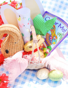 Easter basket for kids using vintage wicker elephant filled with coloring books, stickers, bunny ears, and chocolate bunnies.
