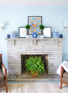Symmetrical arrangement for a preppy traditional mantel in blue and white with pops of orange and green.