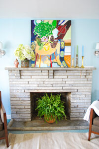 Bright mantel with abstract painting, hydrangea arrangement, and brass candlesticks for summer decorating ideas