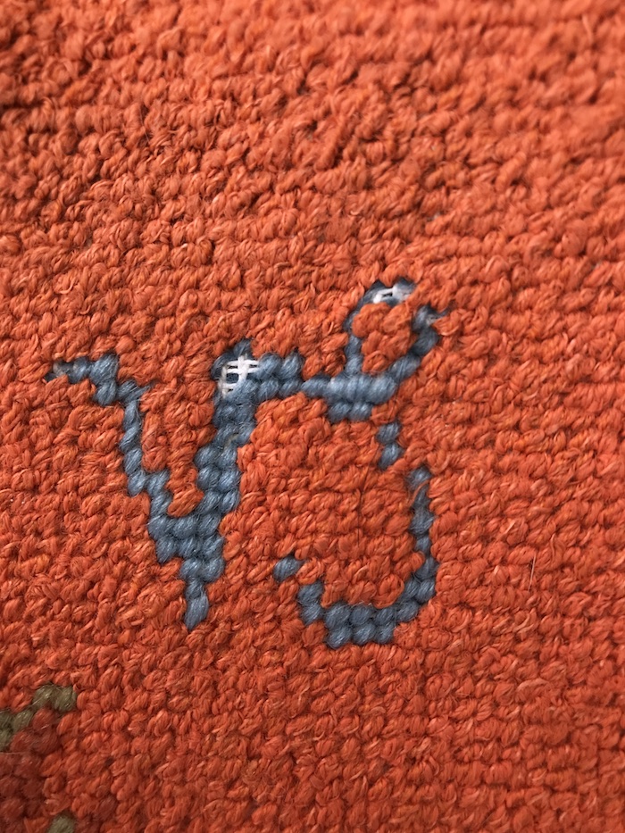 Vintage needlepoint Capricorn symbol with orange background - missing stitches