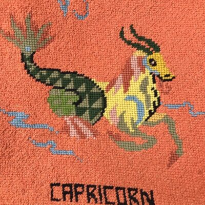 Vintage needlepoint Capricorn symbol with orange background