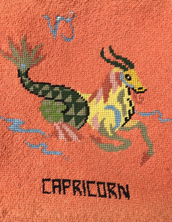 Vintage needlepoint Capricorn symbol with orange background