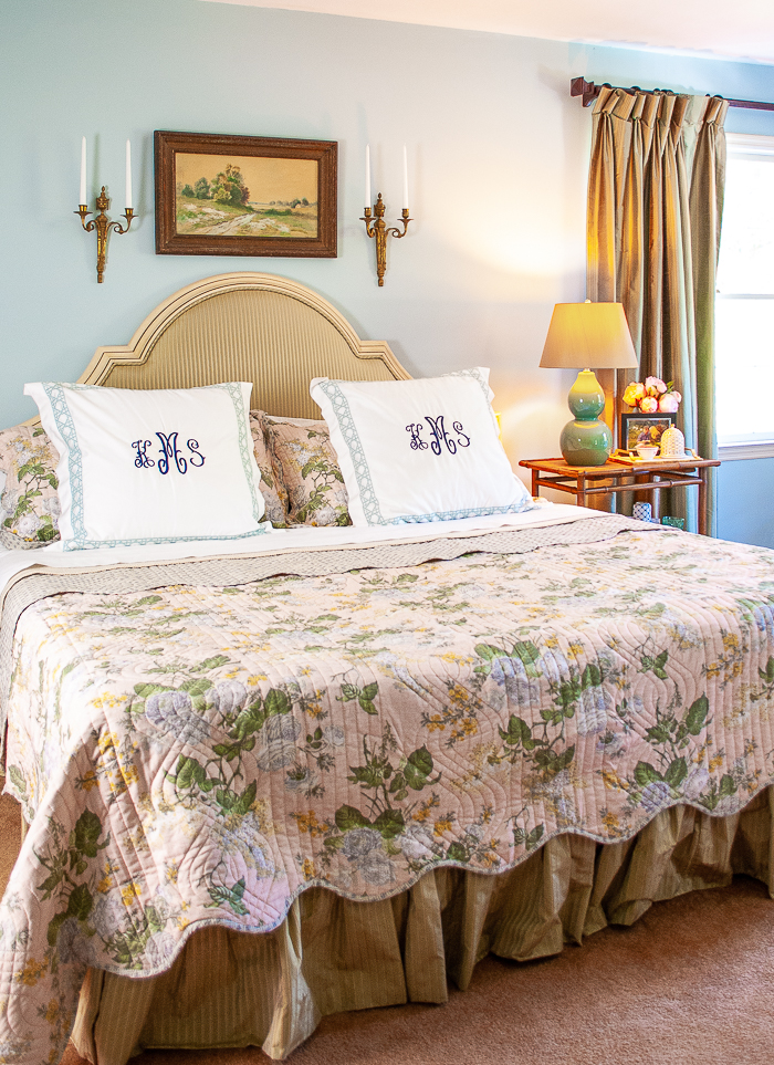 Made bed in grandmillennial bedding including pink chintz quilt, monogrammed pillows, and percale sheets.