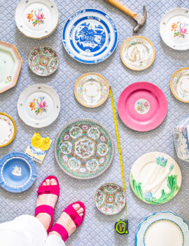 Top down perspective of varied vintage plates laid out on rug with hammer, nails, and measuring tape. Great way to curate a plate wall display.