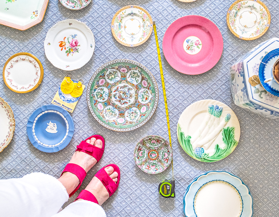 Vintage plates laid out on rug to curate a plate wall with Katherine's feet in the corner.