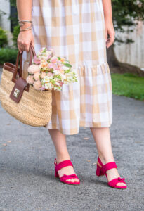 Katherine in gingham dress with straw handbag and sassy pink sandals from Sarah Flint