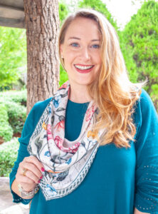 Portrait view of Katherine wearing floral silk scarf tied in cowboy bib style.