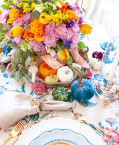 Pumpkins in various sizes, shapes, textures, and colors nestled around floral centerpiece.
