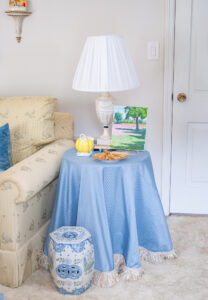 Skirted side table with blue fabric, yellow mottahedeh pumpkin, and landscape painting