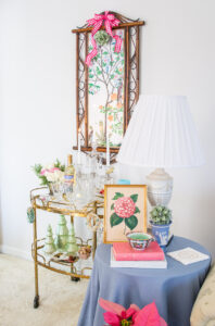 Skirted side table with camellia print, books, and Wedgwood - brass bar cart in background