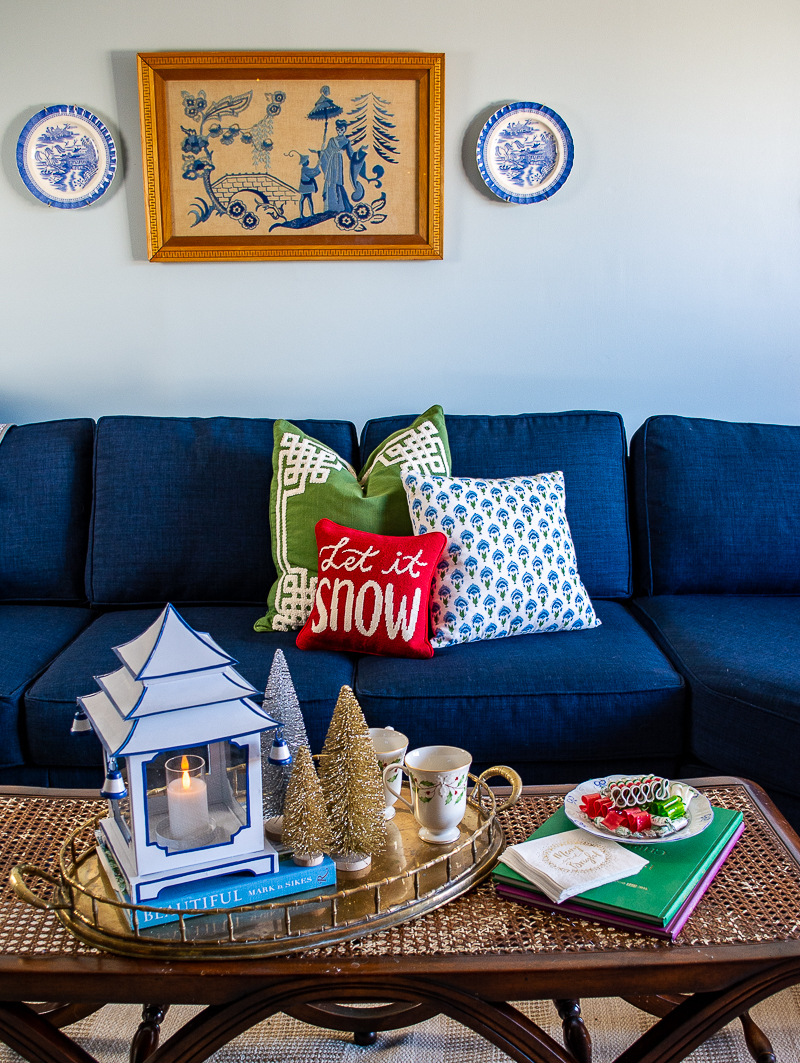 Navy blue sectional sofa with needlepoint pillow and Chinoiserie art on wall above