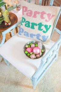 Party party party pillow on rattan chair with bowl of pink and green ornaments