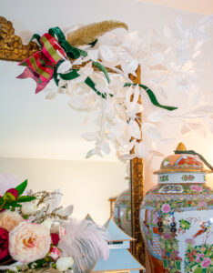 White paper branch hung from gilt mirror above mantel